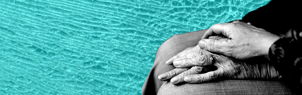 Black and white hand of younger person holding a more wrinkled hand of an older person.