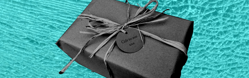 Black and white parcel with label reading "Gift to me xxx" on background of blue shattered glass.